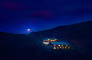 乌提Destiny - The Farm Resort的夜晚在山丘上与月亮相映的房屋