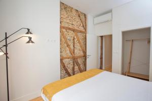 里斯本Montebelo Lisbon Downtown Apartments的卧室配有白色的床和砖墙
