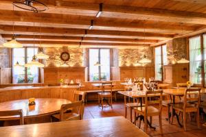 Brunegg三颗星浪漫酒店的餐厅设有木桌、椅子和窗户。