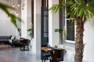 埃因霍温Hotel Mariënhage的一间设有桌子和棕榈树的用餐室