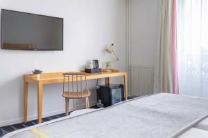 巴黎洛雷特阿斯托特尔酒店的一间卧室配有一张桌子、一台电视和一把椅子
