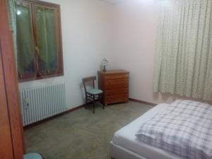 法纳诺RIVAROLA的一间卧室配有一张床、梳妆台和椅子