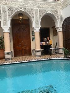 马拉喀什Riad Abaka hotel & boutique的坐在游泳池旁桌子上的女人