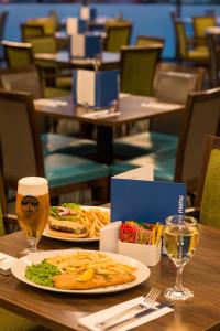 斯劳快捷假日伦敦希斯罗T5航站酒店的一张桌子,上面放着一盘食物和一杯啤酒