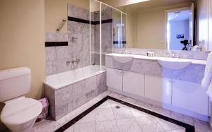 墨尔本弗林德斯兰丁公寓的浴室配有卫生间、浴缸和水槽。