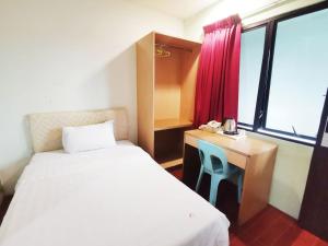 古晋Homestay Kuching Hotel的客房设有两张床、一张桌子和一个窗户。