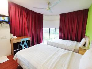 古晋Homestay Kuching Hotel的一间卧室配有两张床、书桌和红色窗帘