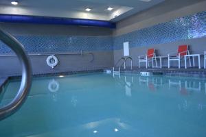 诺克斯维尔诺克斯维尔智选假日酒店的一个带红色椅子的游泳池和一个游泳池