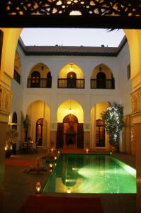 马拉喀什雷亚德夏玛套房酒店及Spa的一座大建筑,在庭院里设有一个游泳池