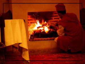 马拉喀什雷亚德夏玛套房酒店及Spa的坐在壁炉旁的男人