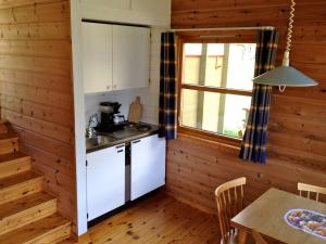 盖郎厄尔峡湾弗约登卡姆平海特酒店的厨房设有木墙、桌子和窗户。