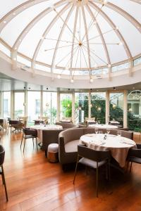 米兰米兰加里波蒂站假日酒店的餐厅设有桌椅和玻璃圆顶天花板。