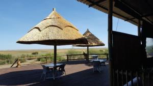 KavimbaMwandi View的甲板上配有两张桌子、椅子和遮阳伞