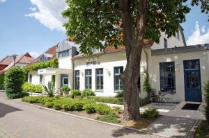 格赖夫斯瓦尔德Ryck-Hotel Garni的前面有棵树的白色建筑