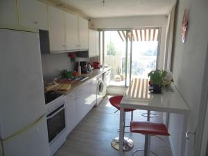 尼斯La Madonette的厨房配有白色橱柜、桌子和窗户。