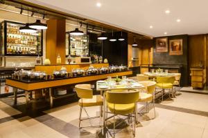 浦那Lemon Tree Hotel Viman Nagar Pune的一间带桌椅的餐厅和一间酒吧