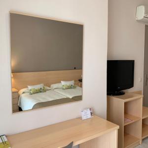 圣卡洛斯拉腊皮塔Hotel Restaurant Llansola的镜子反射着卧室,卧室配有一张床和电视