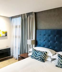 布隆方丹Premier Splendid Inn Bloemfontein的酒店客房,设有一张床和一个蓝色的床头板