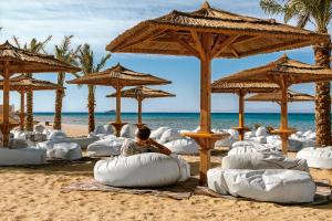 赫尔格达Robinson Soma Bay的坐在海滩上的人,带枕头和遮阳伞