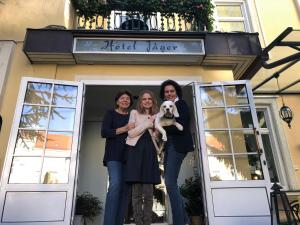 维也纳Hotel Jäger - family tradition since 1911的三个女人站在一扇门前,带着一只狗