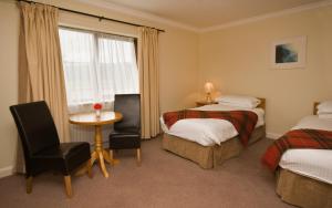 伦维尔Renvyle House Hotel & Resort的酒店客房设有两张床、一张桌子和一个窗户。