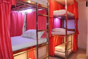 奥拉奇哈Sunset Backpackers Hostel的一组双层床,位于一个红色窗帘的房间