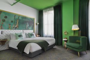 圣路易斯Angad Arts Hotel的绿色卧室,配有床和绿色椅子