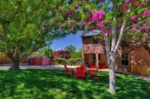 摩押Cali Cochitta Vacation Rentals的一个带红色椅子的院子和一棵种有粉红色花的树