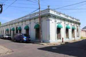 圣安娜Hostal Plaza Antigua的街道上带有绿色遮阳篷的白色建筑