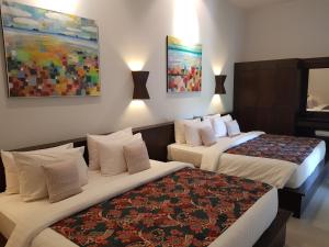 高兰Tropicana Lanta Resort的酒店客房设有两张床,墙上挂有绘画作品