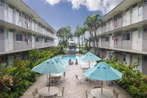 檀香山太平洋码头酒店的一个带桌子和遮阳伞的庭院和一个游泳池