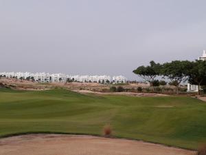 罗尔丹Las Terrazas Golf Resort Rental的享有高尔夫球场绿地的景色,建筑背景