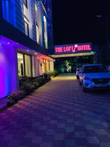 西里古里The Loft Hotel, Siliguri的晚上在酒店前面的一个停车场