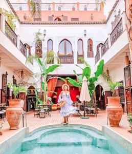 马拉喀什帕查瓦娜庭院旅馆的站在房子里游泳池前的妇女