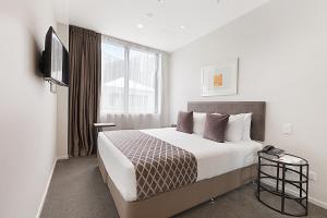 奥克兰Ramada Suites Victoria Street West的酒店客房,配有床和电视