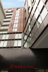 奥克兰Ramada Suites Victoria Street West的享有高楼的景色,设有红色的兰巴第标志