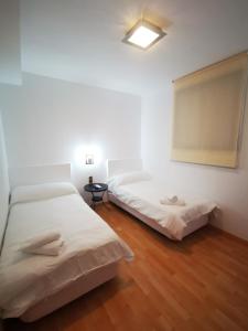 埃纳雷斯河畔圣费尔南多Hostal Quinta Santillan的配有白色墙壁和木地板的客房内的两张床