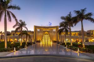 赫尔格达Pickalbatros Aqua Blu Resort - Hurghada的享有棕榈树建筑前方的景致