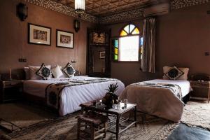 瓦尔扎扎特瓦尔扎扎特庭院旅馆 的一间卧室设有两张床、一张桌子和一个窗口