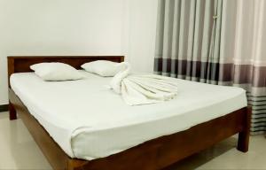 马哈拉贾马Kanora lake resort的一张带白色床单和枕头的床