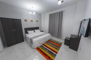 阿尔哈德Al Sqlawi Hotel Apartment的一间卧室配有一张床、一台电视和一张地毯。