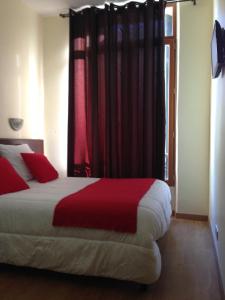马赛胜利酒店的一间卧室配有一张带红色床单的床和一扇窗户。