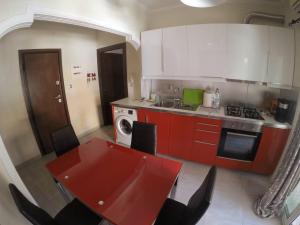 科孚镇Cozy and modern apartment的厨房配有红色桌子和炉灶 顶部烤箱