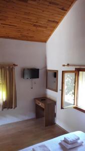 契拉勒阿米娜膳食酒店的一间卧室配有一张桌子和一台墙上的电视。
