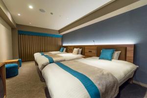 高山飞弹高山瓦特酒店及Spa的酒店客房,配有3张带蓝色枕头的床