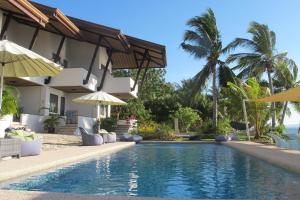 奥斯洛布Emoha Dive Resort的一座带遮阳伞的房屋前的游泳池