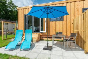 德科赫Chalet studio Mees - Texel的庭院配有桌椅和蓝伞。
