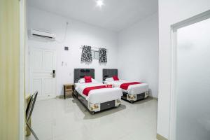 棉兰RedDoorz Plus near Thamrin Plaza Medan的白色墙壁客房的两张床