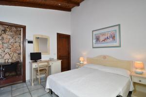 圣特奥多罗Li Suari Club Village的一间卧室配有一张床、一张书桌和一台电视