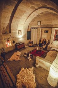 乌奇希萨尔Asmalı Cave House的坐在壁炉旁的男人和两只狗